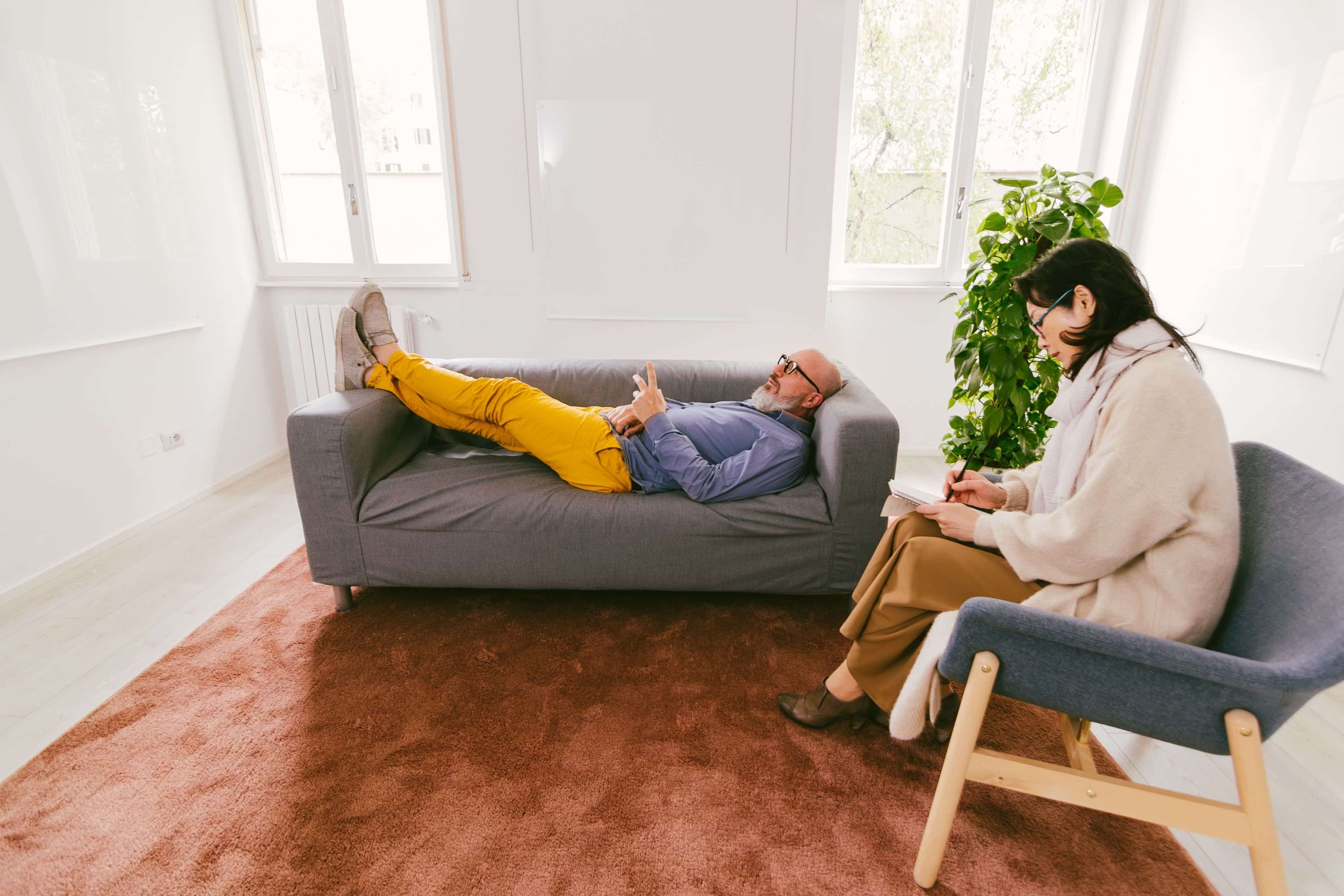 man in therapy at psychologist lying on couch