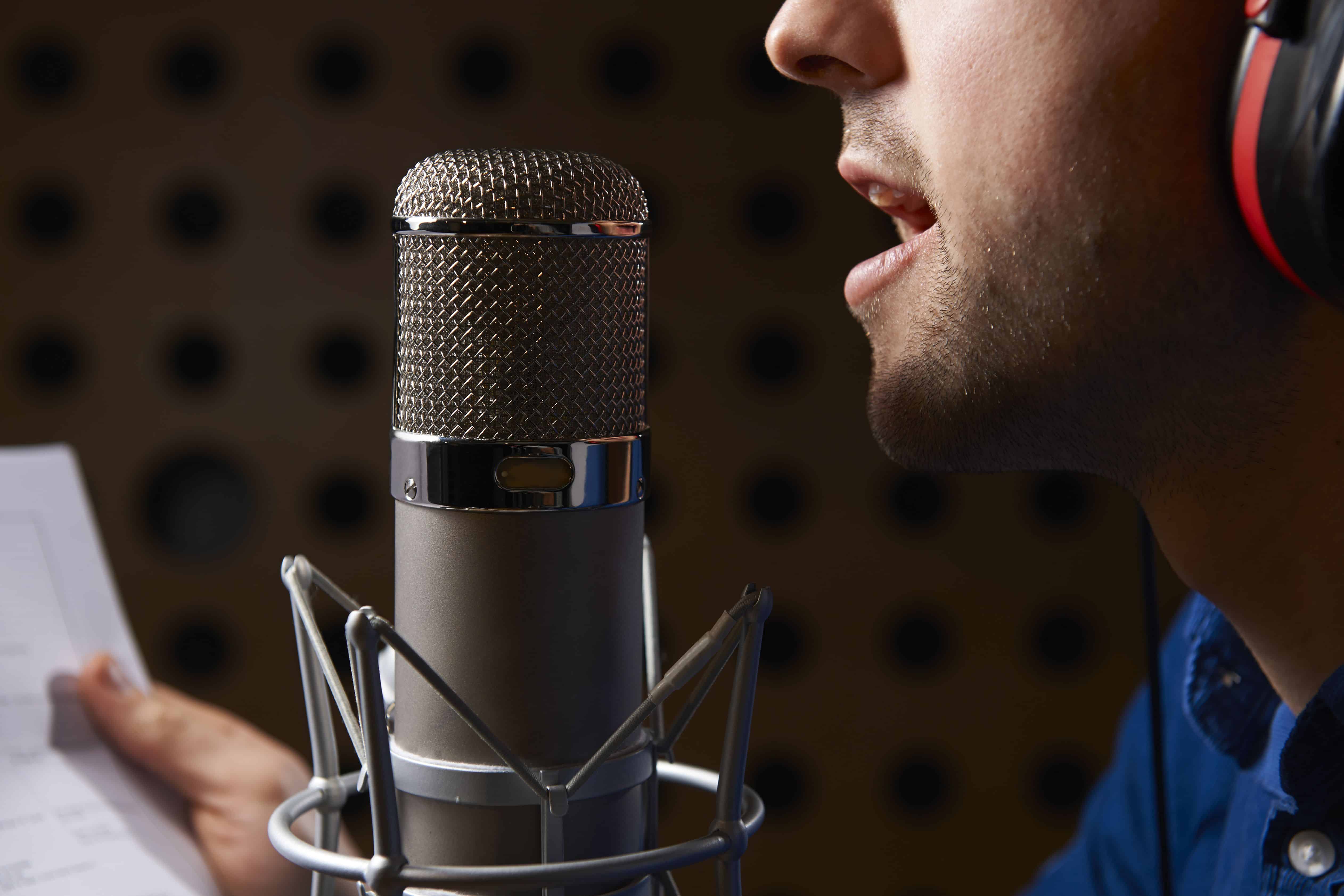 Man Holding Notes And Talking Into Studio Microphone