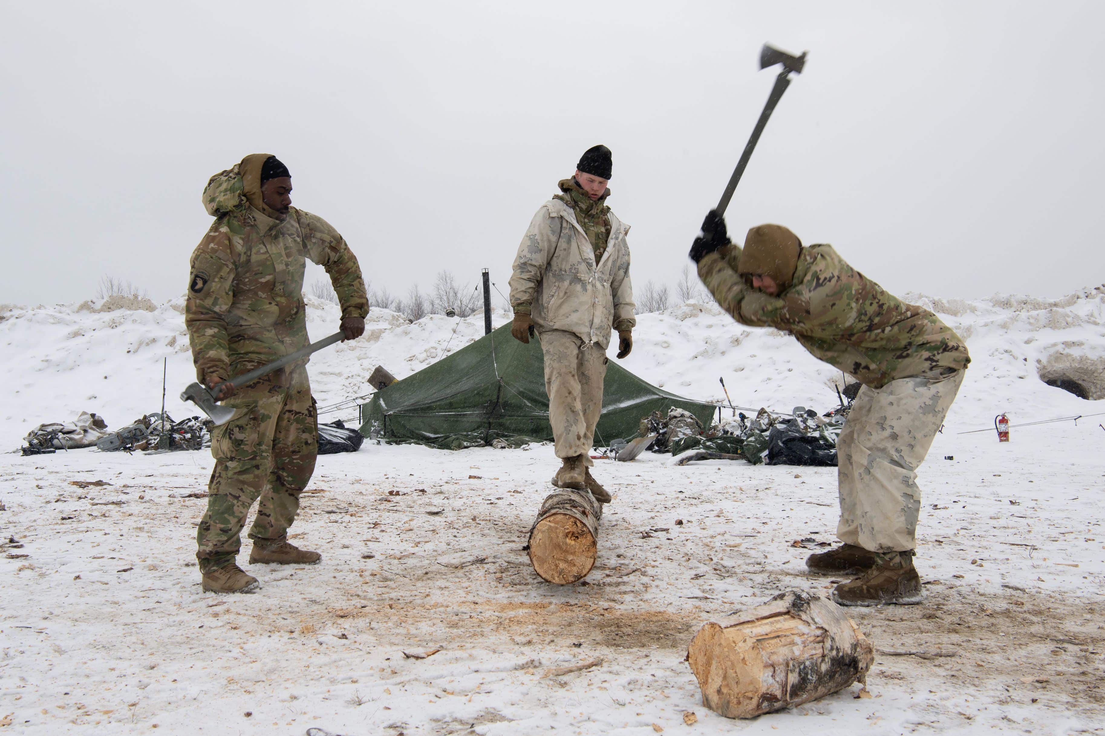 U.S. Army infantrymen with B Company, 1st Battalion, 5th Infantry Regiment, 1st infantry Brigade Combat Team, 11th Airborne Division, chop fire wood during a lull in fighting while acting as opposition forces for Joint Pacific Multinational Readiness Center-Alaska 23-02 at Yukon Training Area