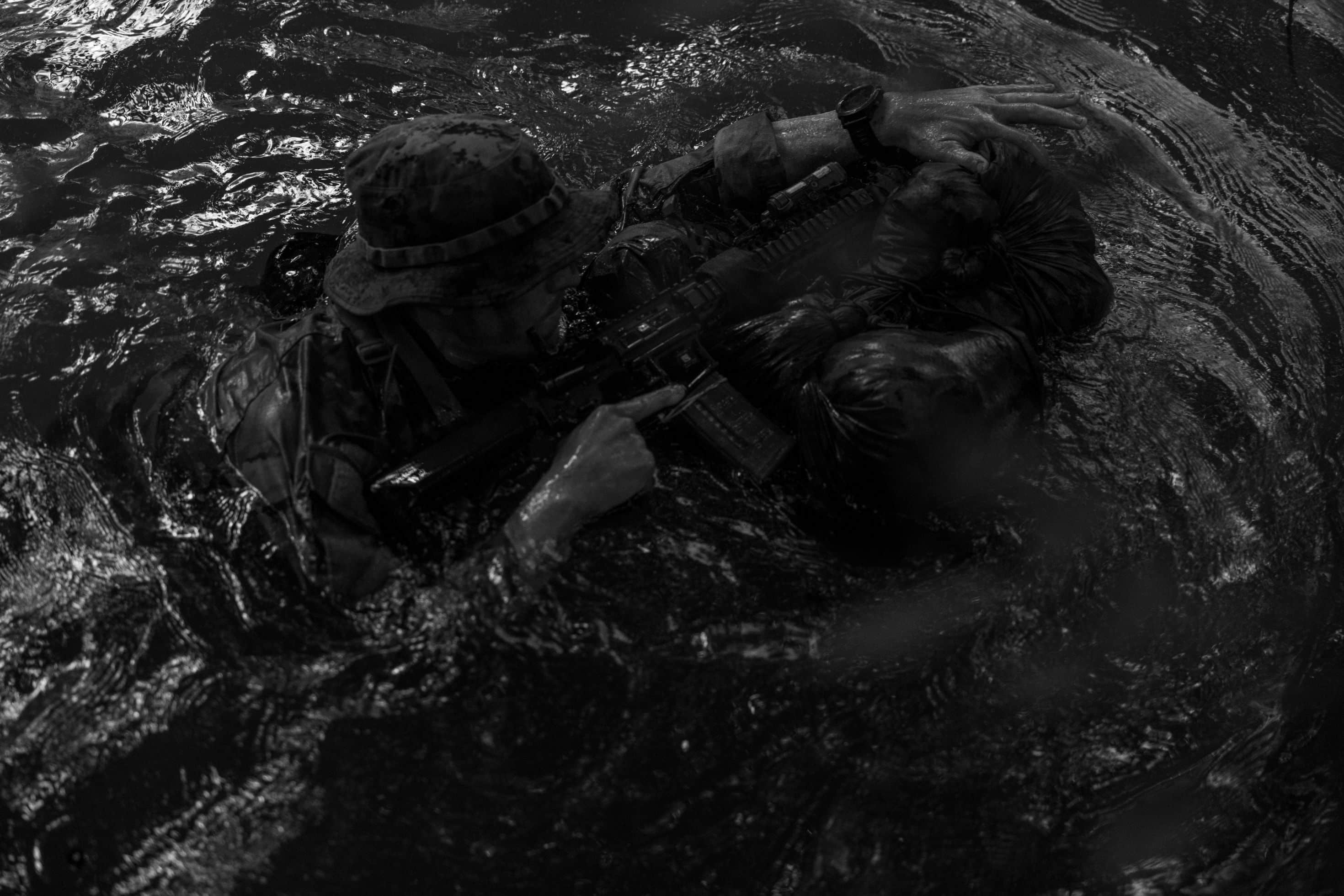 A Marine Raider with Marine Forces Special Operations Command traverses a river during a jungle mobility course, Aug. 4, 2023. Marine Raiders in the training program learned to maneuver in a jungle environment, conceal their movements, and track adversary movements. (U.S. Marine Corps photo by Cpl. Henry Rodriguez) (This photo was edited in black and white for artistic purposes)