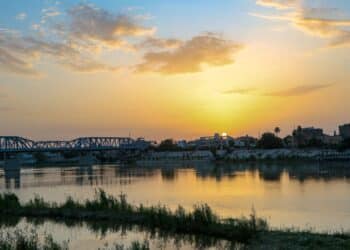 Baghdad, Iraq – April 4, 2020: photo for sunrise in Baghdad city in Iraq, which showing the Sarafia Bridge and Tigris river, and many of buildings.