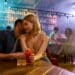 Young man and woman flirting in the bar, enjoying drinks and conversation. Love, couple, romance concept. Selective focus. Horizontal shot