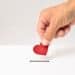 Red heart symbol is put by person's hand into slot of white donation box, Concept of donorship, life saving or charity