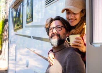 Vacation on camper van for adult people enjoying nature and free parking. Man and woman couple in travel holiday on motor home off grid lifestyle. Female hug male with love and intimacy. Green