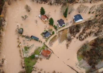 Flooded village, fields, farms and houses, aerial drone view. Aftermath of devastating river flood and landslide. Catastrophic floods. Overflowing river, view from above.