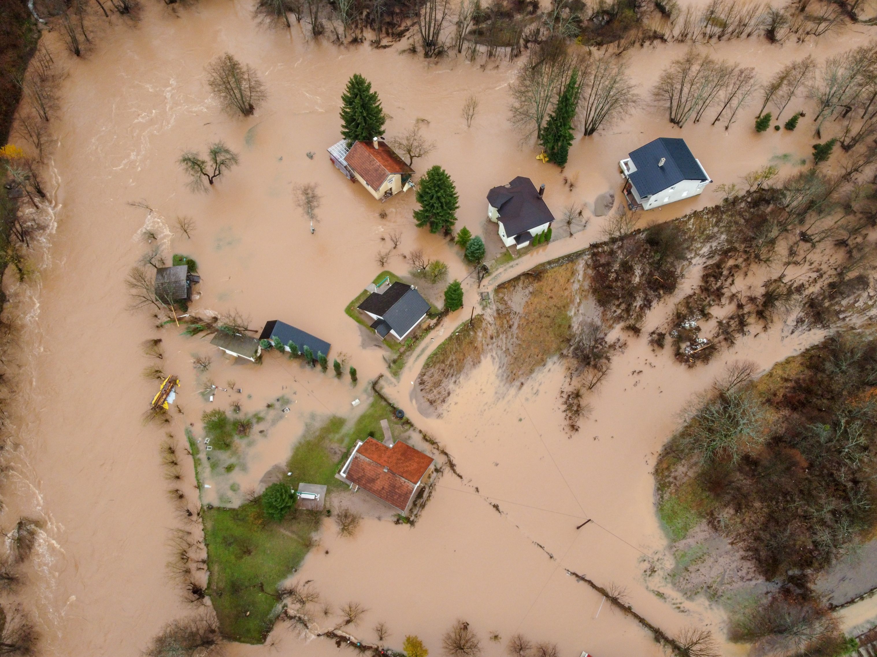 Flooded village, fields, farms and houses, aerial drone view. Aftermath of devastating river flood and landslide. Catastrophic floods. Overflowing river, view from above.