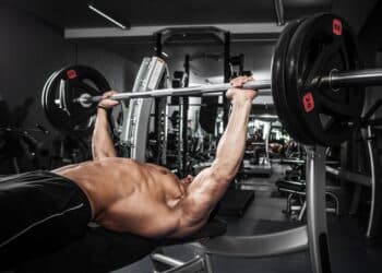Brutal athletic man pumping up muscles on bench press