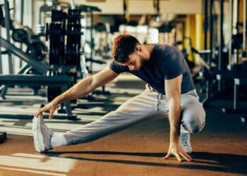 Handsome man doing warm up in the gym and stretch legs