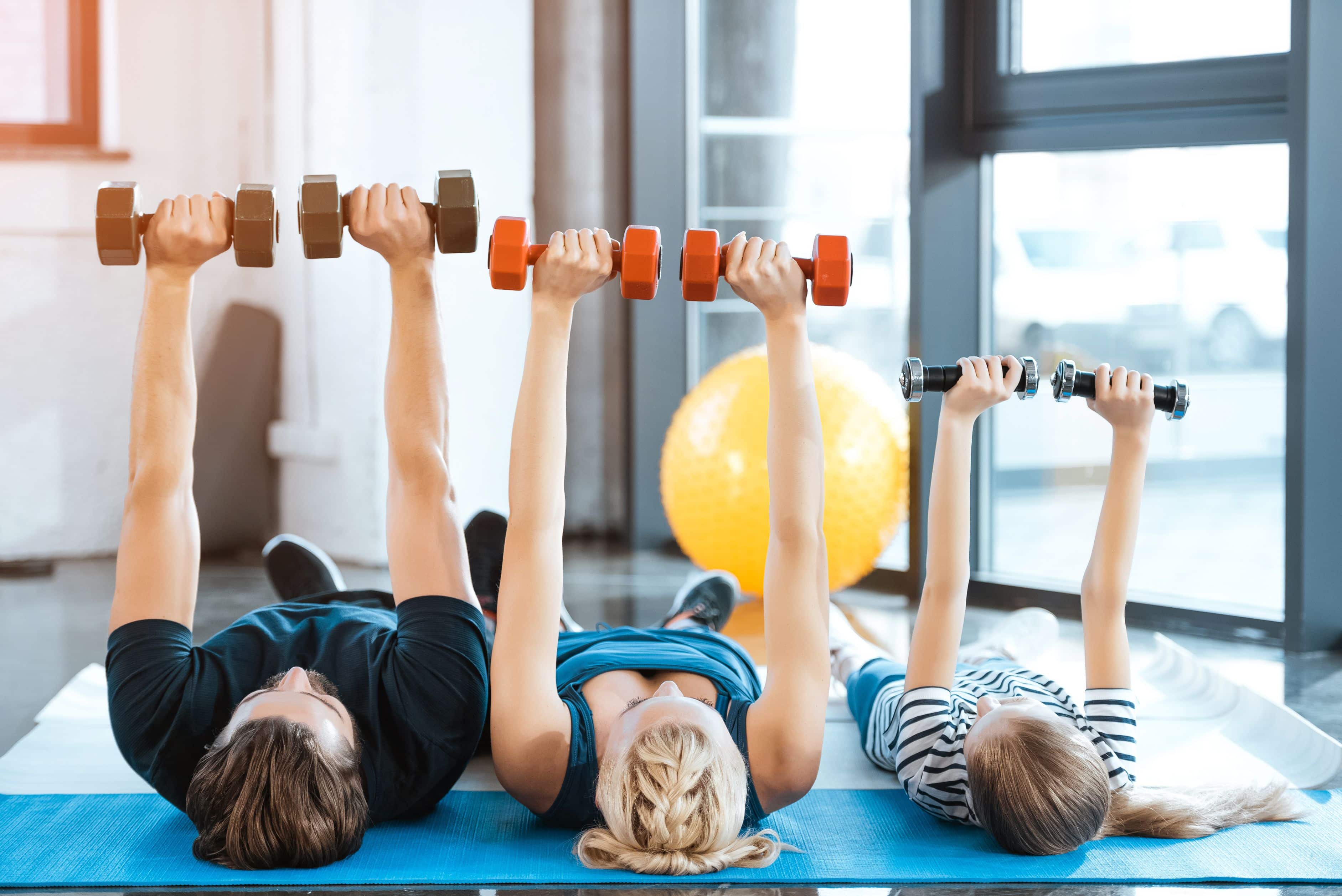 Happy family exercising with dumbbells at fitness studio