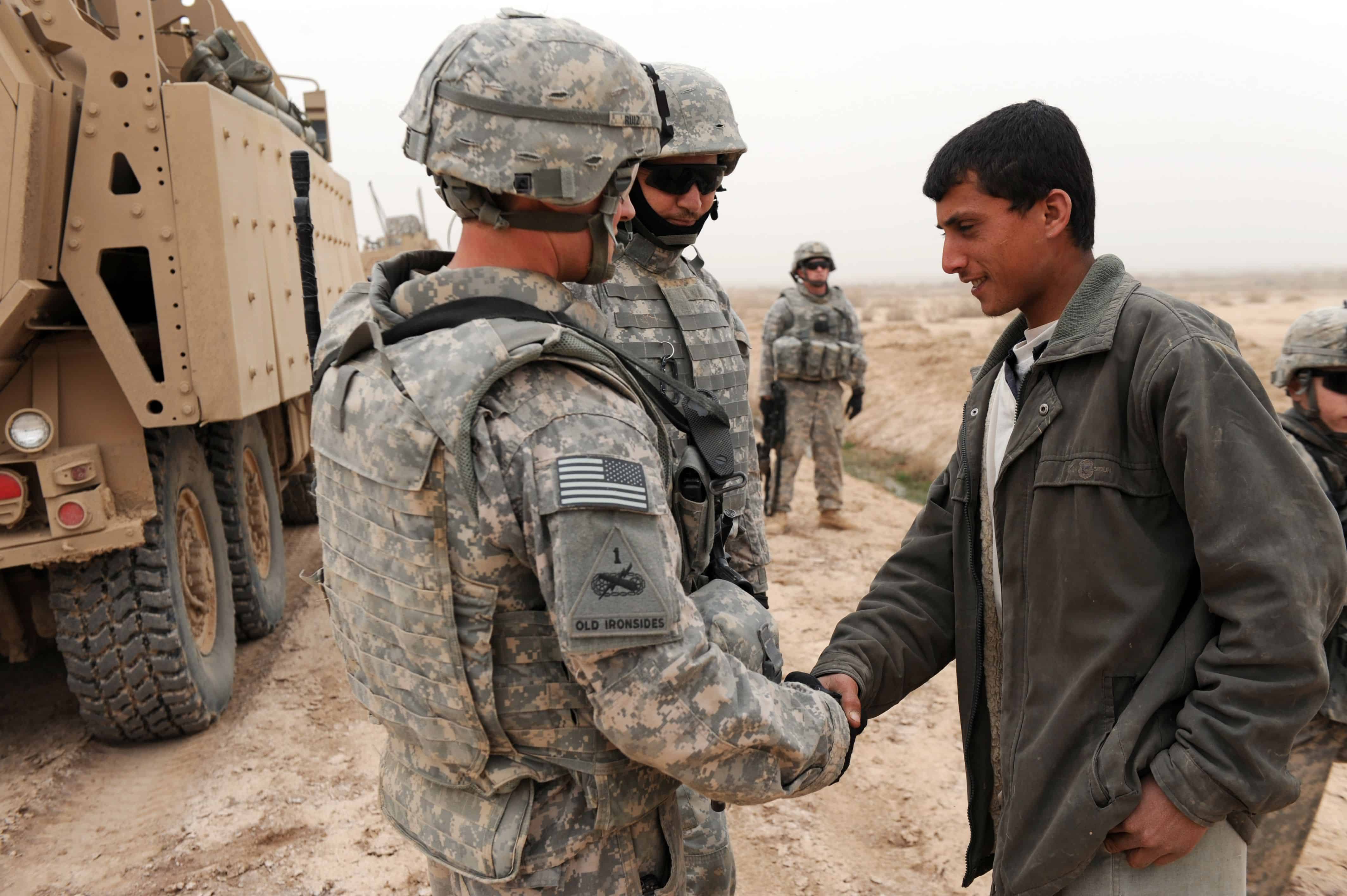 U.S. Army 1st Lt. Lorenzo Ruiz, Platoon Leader, 2nd Platoon, Bravo Company, 1st Brigade, 37th Battalion, 1st Brigade Combat Team, 1st Armored Division, from Edinburg, Texas, shakes hands with a young famer during an Indirect Fire Patrol near Al-Mustafia, Iraq, Feb. 23. U.S. Soldiers conduct IDFs to find evidence of mortar launch sites or attacks against military instillations.