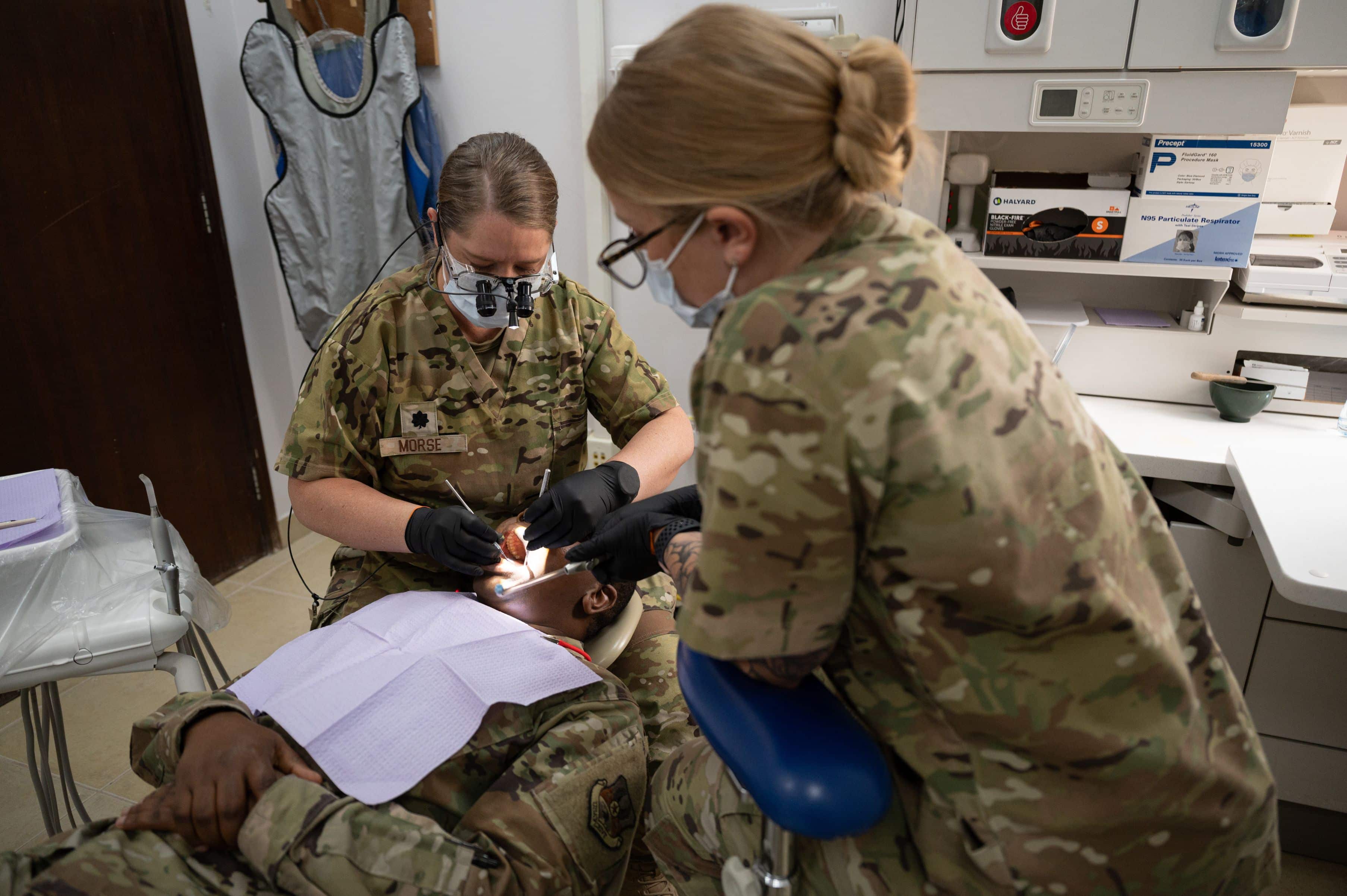 U.S. Air Force Lt. Col. Paula Morse, chief of dental services, 386th Expeditionary Medical Group, performs a dental examination on Capt. Koech C. Bellion, public health officer, 386th EMDG, while Tech. Sgt. Shannon Raaymakers, noncommissioned officer in charge of dental services, 386th EMDG