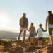 Rear View Of Family Standing At Top Of Hill On Hike Through Countryside In Lake District UK