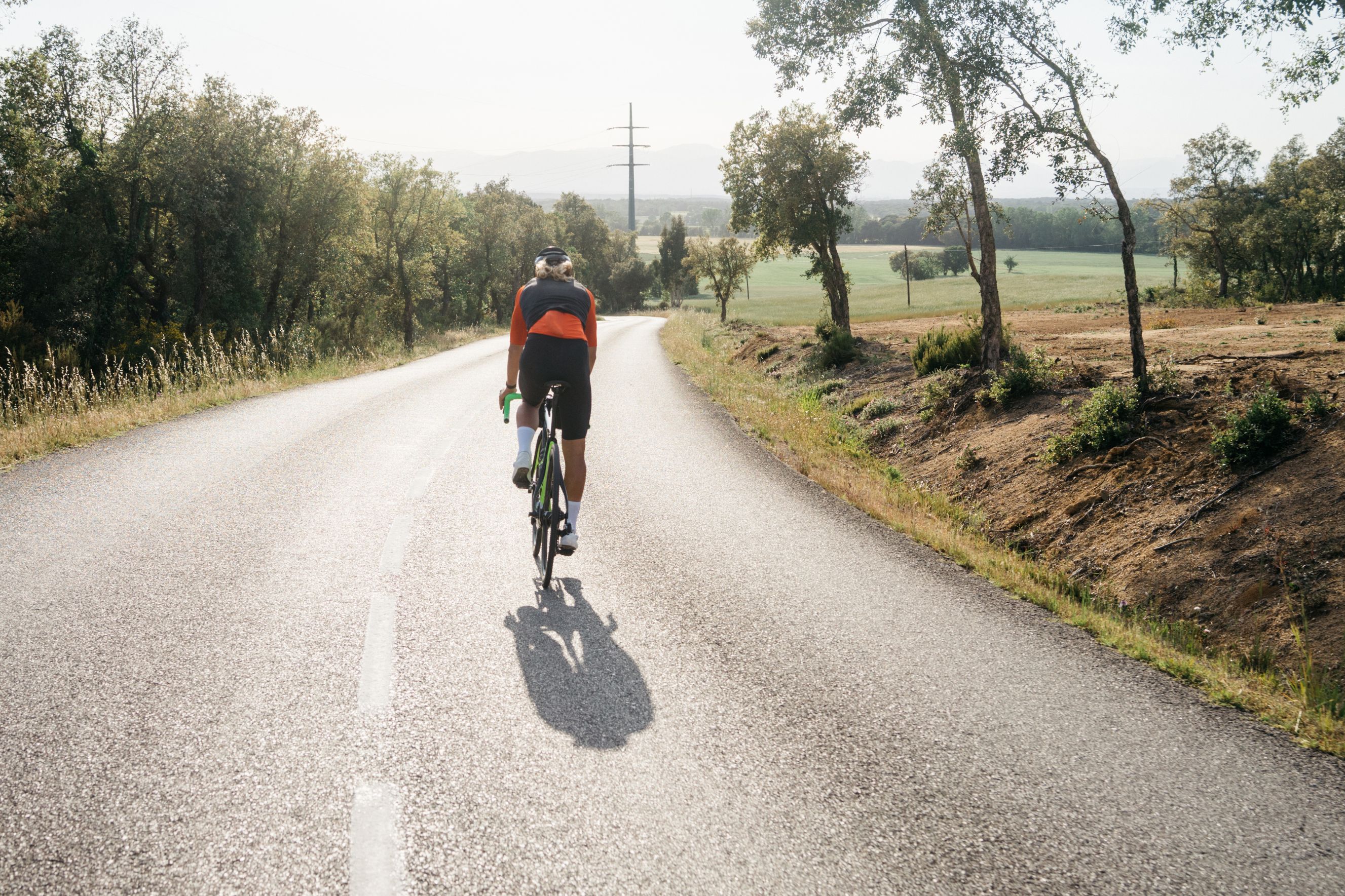 Male cyclist back view, ride solo in a gravel road in the nature. Beautiful motivation image of an athlete during summer bike ride. Sportsman training hard on bicycle outdoors at sunset