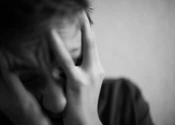 A 18 year old teenager covers his face in despair with his hand