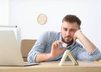Lazy young office employee procrastinating at workplace