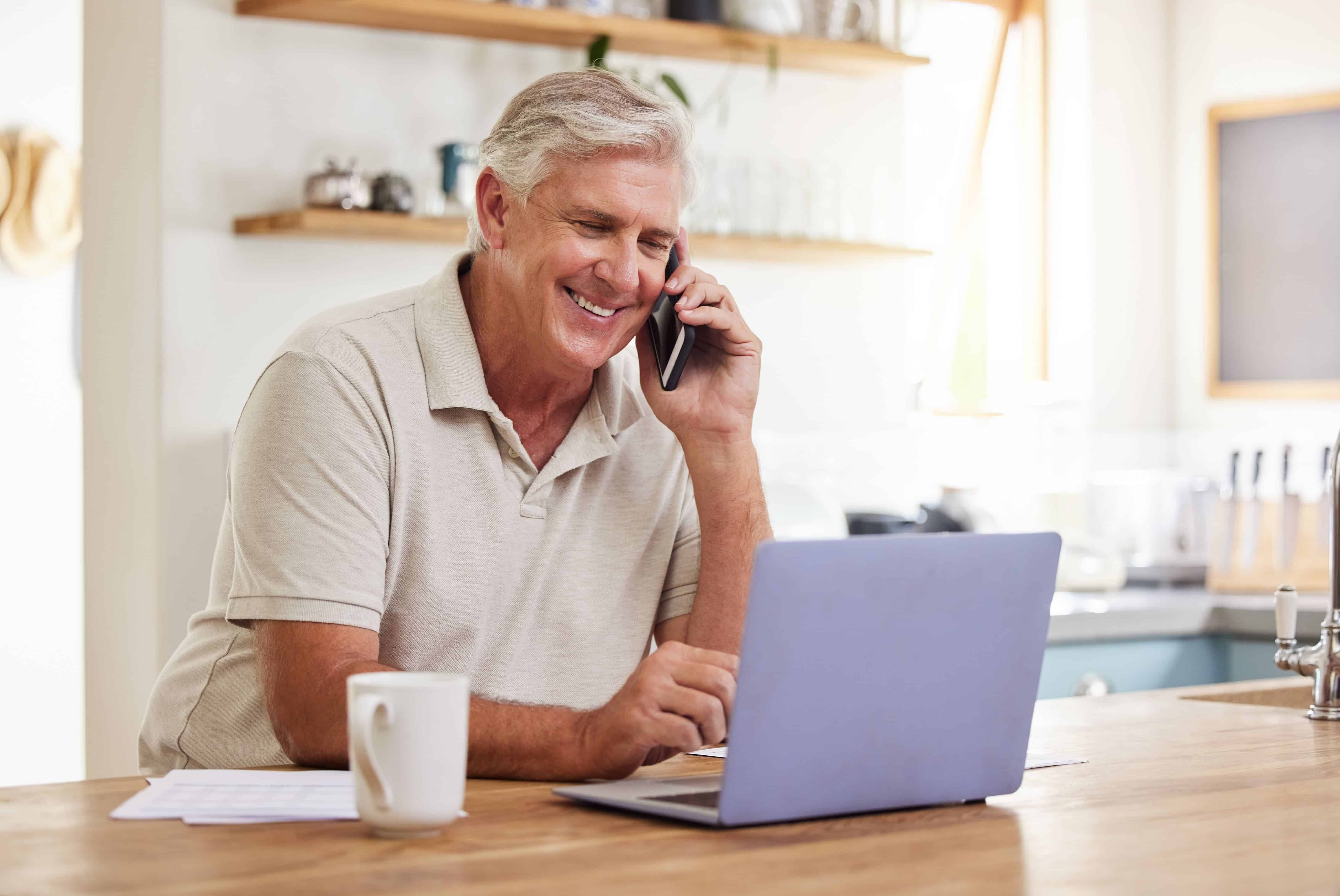 Senior man, phone call and laptop home budget finances, online banking and planning for retirement savings, investment and insurance. Happy mature guy working, consulting and mobile admin connection