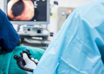A doctor or surgeon in a light blue protective gown did a colonoscopy or gastroscopy inside operating theatre in the hospital.EGD technology for cancer screening.Blur green background and foreground.