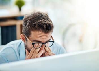 Business man, headache and pain, tired or fatigue in office while working on pc. Burnout, migraine and male person with depression, vertigo or brain fog, anxiety or mental health, stress or problem.