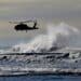 LONG BEACH, US - Apr 19, 2021: A vertical of the silhouette of a helicopter flying above the big foamy waves at the Washington Coast