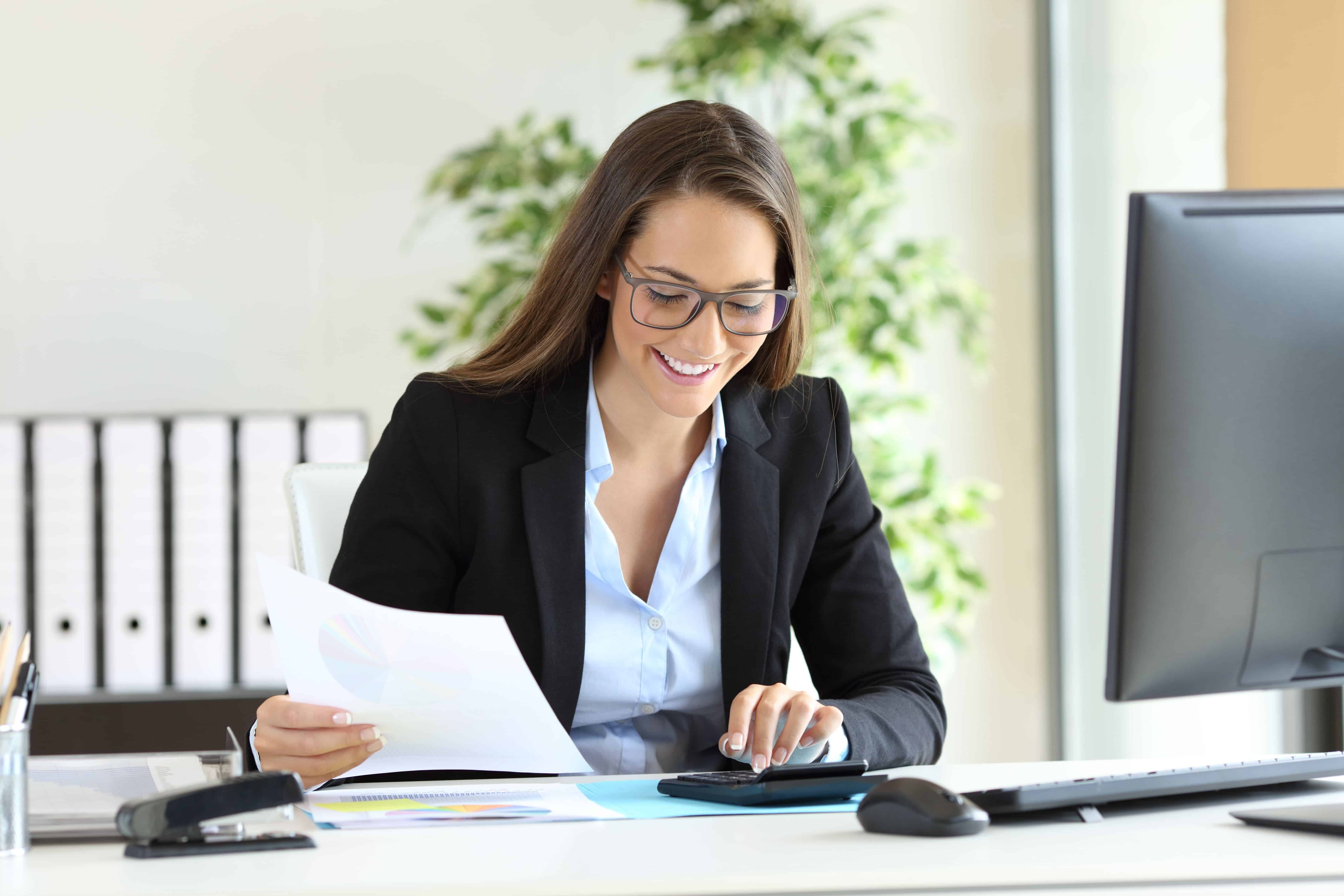 Happy businesswoman wearing suit working using a calculator in a desk at office