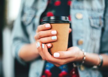 Female hand with paper cup of coffee take away.
