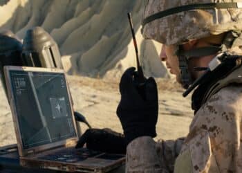 Soldier is Using Laptop Computer for Tracking the Target and Radio for Communication During Military Operation in the Desert