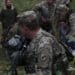U.S. Army Sgt. Clayton Hildebrandt, a civil affairs noncommissioned officer with the Civil Military Operations Center, looks over his shoulder as Ukraine soldiers administer first aid to a simulated casualty during the medical situational training exercise, as one of the training objectives for Rapid Trident 2019 in Yavoriv, Ukraine, Sept. 19, 2019.