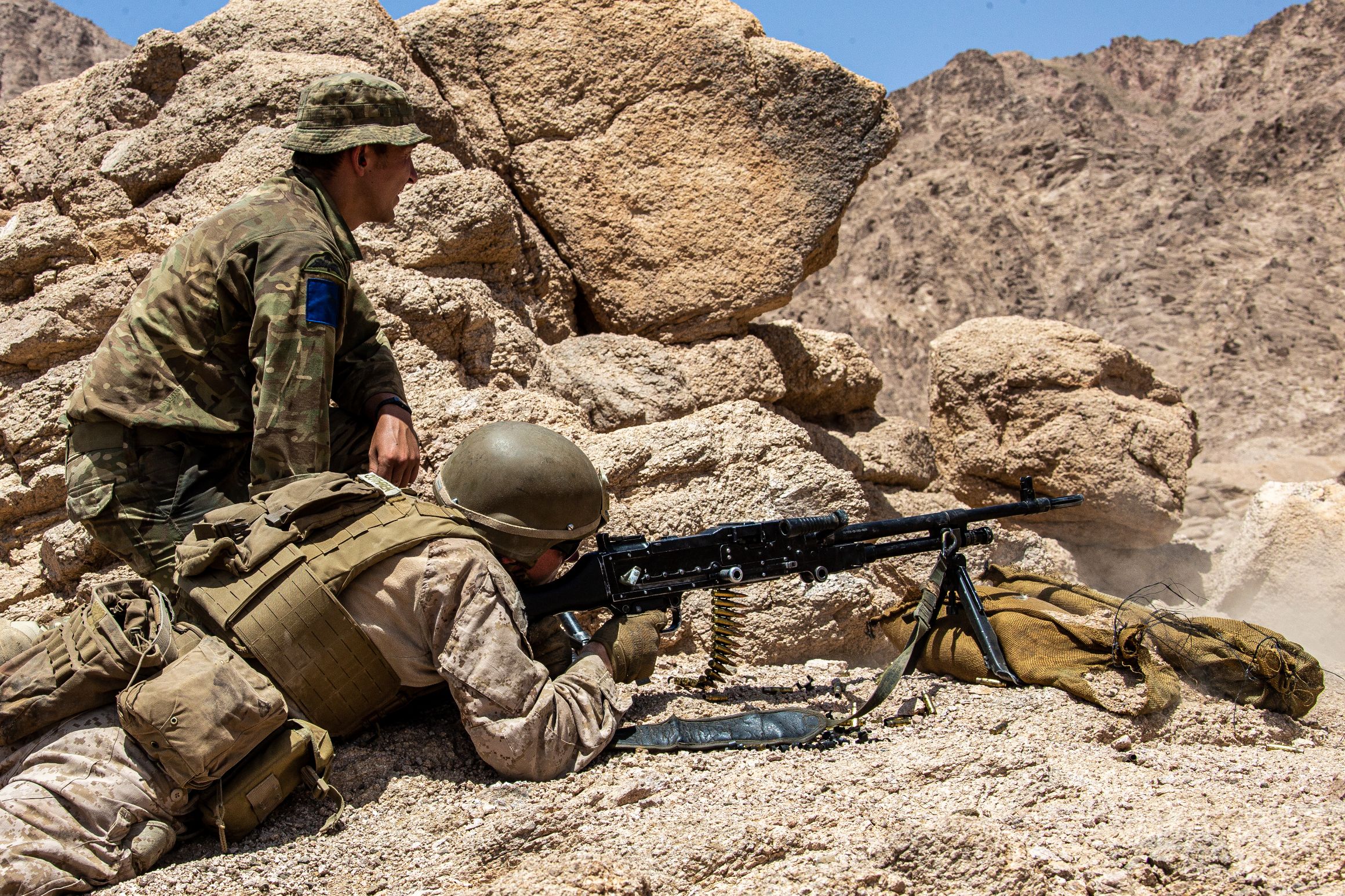 A U.S. Marine with 2nd Battalion, 1st Marines, attached to the Special Purpose Marine Air – Ground Task Force – Crisis Response - Central Command (SPMAGTF-CR-CC) 21.1, fires a L7A2 General Purpose Machine Gun while being observed by a British Army Soldier with 2nd Battalion, Parachute Regiment
