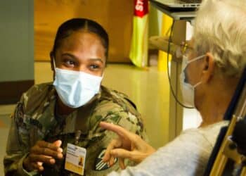 SYRACUSE--Pvt. Nastasia Morgan, a combat medic assigned to the 107th Military Police Company, 369th Sustainment Brigade, sits with a resident at Loretto Health and Rehab in Syracuse, NY Dec. 20. As part of New York State's response to Covid-19, National Guard medics have been deployed in nursing homes to help alleviate congestion of the state’s healthcare system (U.S. Army photo by Staff Sgt. Alexander Rector / released).