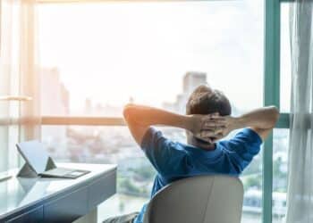 Life-work balance and city living lifestyle concept of business man relaxing, take it easy in office or hotel room resting with thoughtful mind thinking of life quality looking forward to cityscape