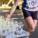 Runner with race number grabbing plastic cup with water at the refreshment station on the race. Focus on cups.