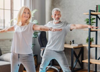 Mature couple practicing yoga and performing warrior yoga pose together