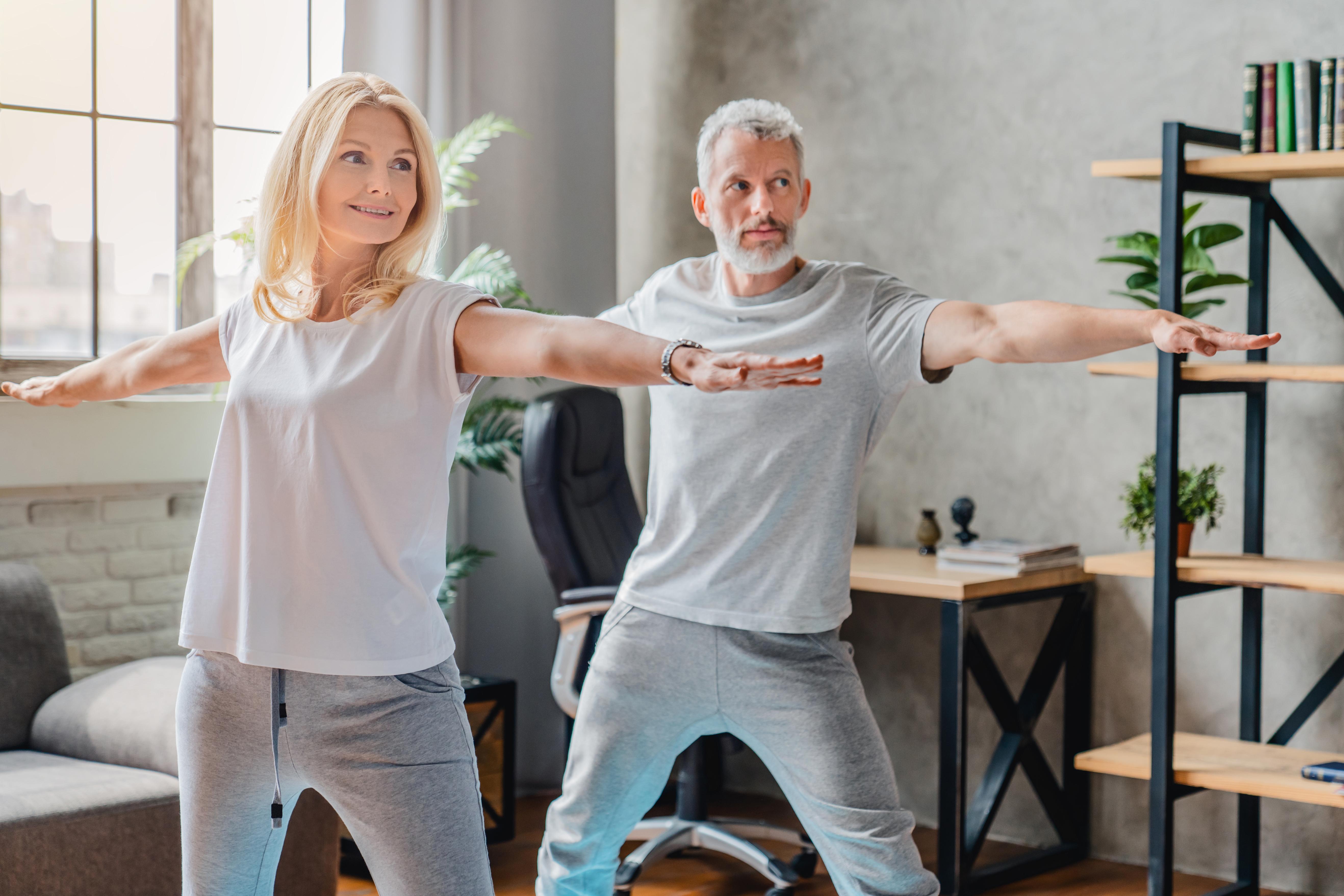 Mature couple practicing yoga and performing warrior yoga pose together