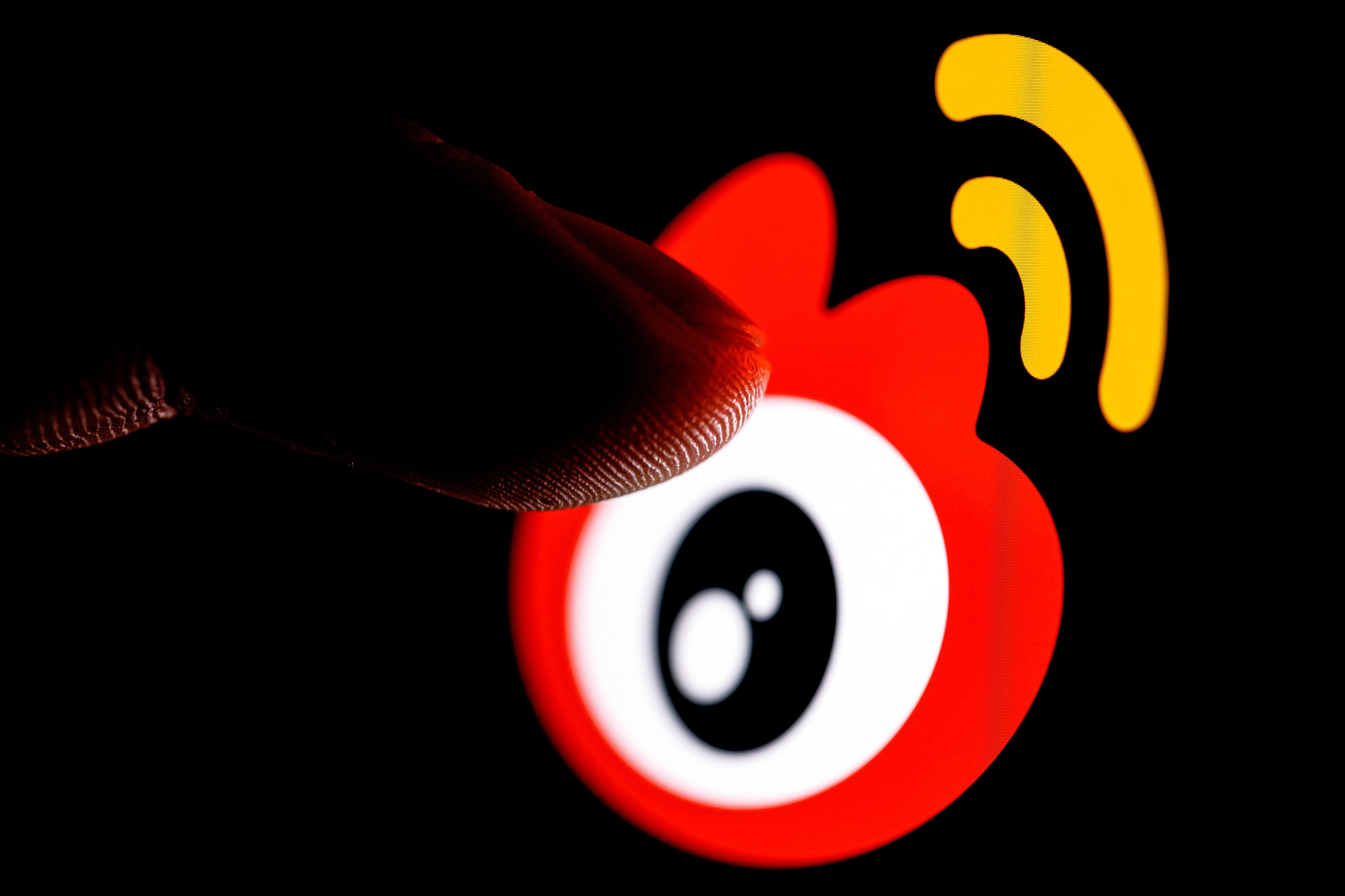 Kazan, Russia - Mar 10, 2022: The finger reaches for Weibo chinese microblogging service logo on smartphone screen.
