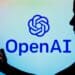 October 7, 2022, Brazil. In this photo illustration, the OpenAI logo is seen in the background of a silhouetted woman holding a mobile phone