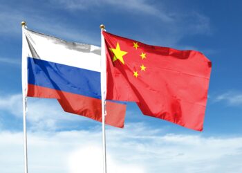 Russian flag and Chinese flag on the cloudy sky. Wave in the sky