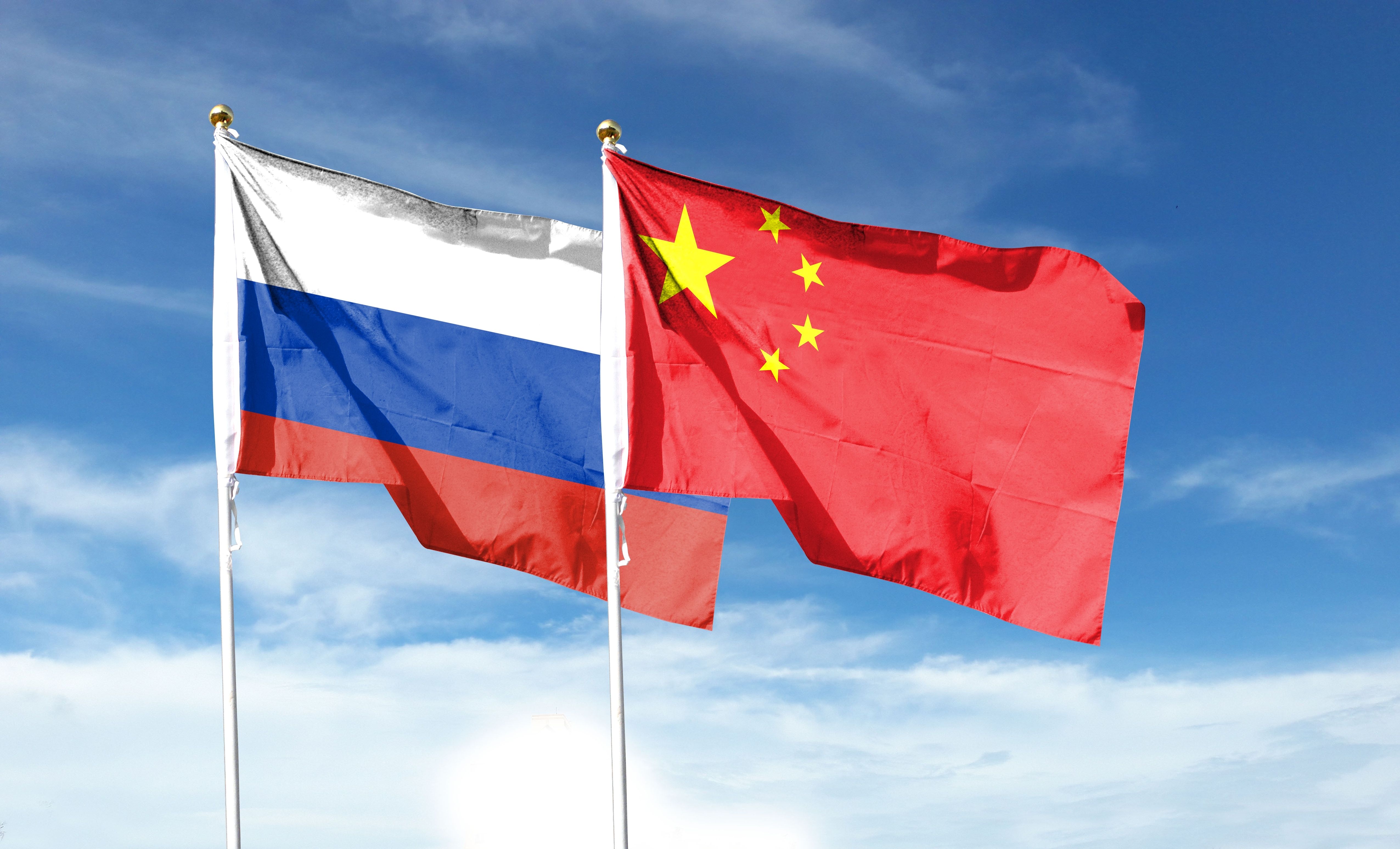 Russian flag and Chinese flag on the cloudy sky. Wave in the sky