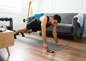 Healthy young man with a fitness lifestyle doing a plank and using the timer app on his smartphone