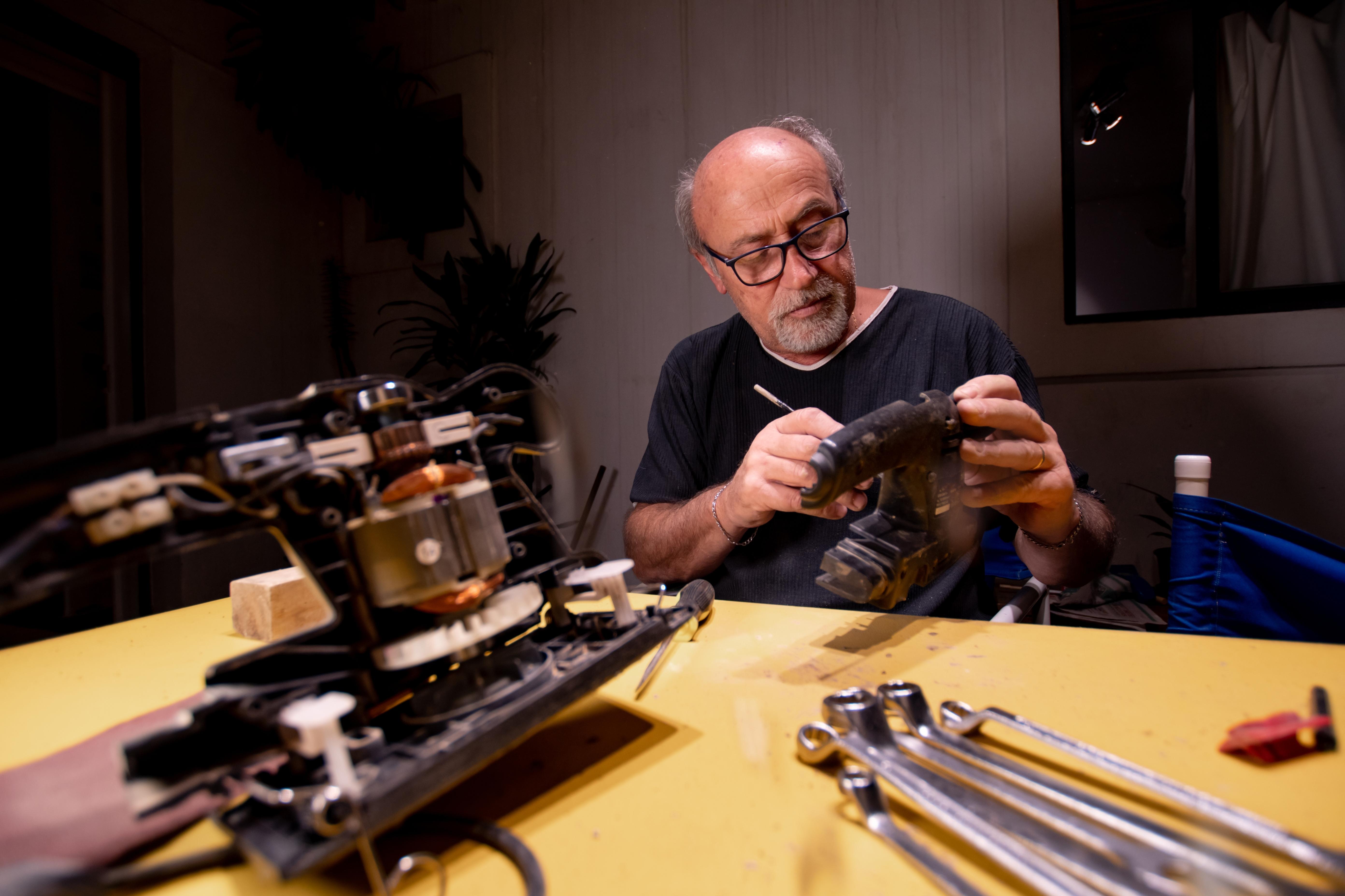 Older man cleaning craft repair items in his workshop