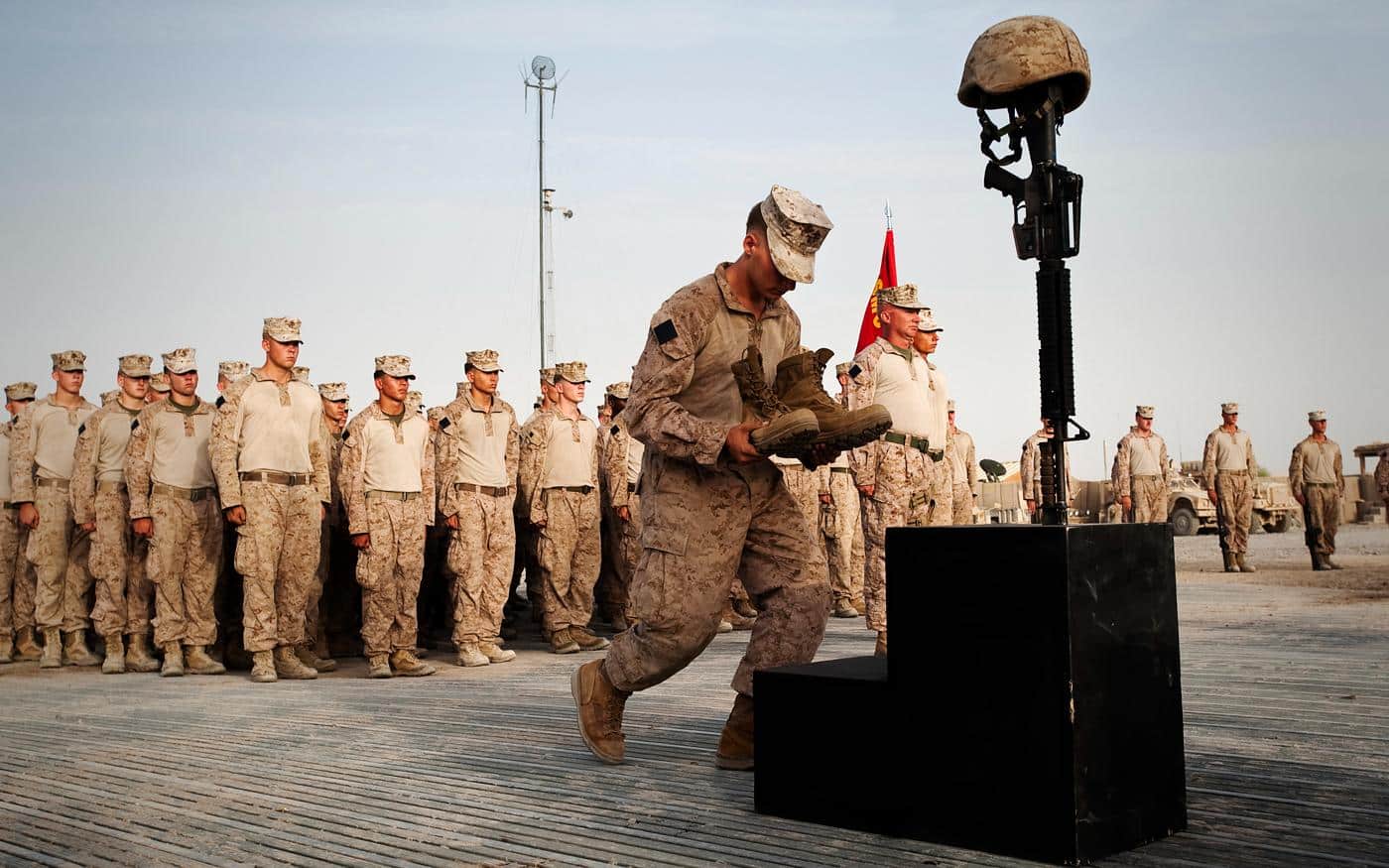 Lance Cpl. Joshua S. Leventhal, a grenadier with Kilo Company, 3rd Battalion, 3rd Marine Regiment, completes Sgt. Joe L. Wrightsman’s battlefield cross by placing boots and identification tags on the monument during a memorial service at Patrol Base Jaker, Afghanistan, July 30. Wrightsman died supporting combat operations July 18.