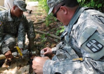 Staff Sgt. Angel Cintron (left), 973rd Quartermaster Company, assists Maj. James J. Houlihan, 1893rd Medical Detachment, obtain a water sample from a bladder of purified water to be tested for micro bacterial contamination. During the nationwide Quartermaster Liquid Logistics Exercise 2011, the 973rd operated the Reverse Osmosis Water Purification Unit that purified water from a local pond used for the Expeditionary Water Packaging System, and for laundry and bath purposes.