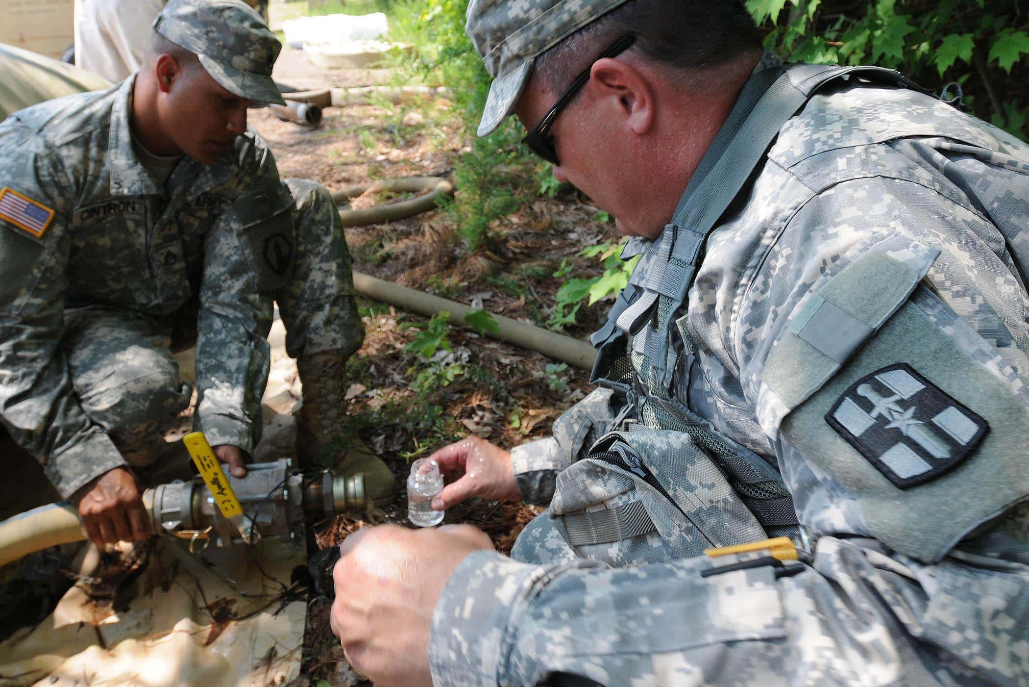 Staff Sgt. Angel Cintron (left), 973rd Quartermaster Company, assists Maj. James J. Houlihan, 1893rd Medical Detachment, obtain a water sample from a bladder of purified water to be tested for micro bacterial contamination. During the nationwide Quartermaster Liquid Logistics Exercise 2011, the 973rd operated the Reverse Osmosis Water Purification Unit that purified water from a local pond used for the Expeditionary Water Packaging System, and for laundry and bath purposes.