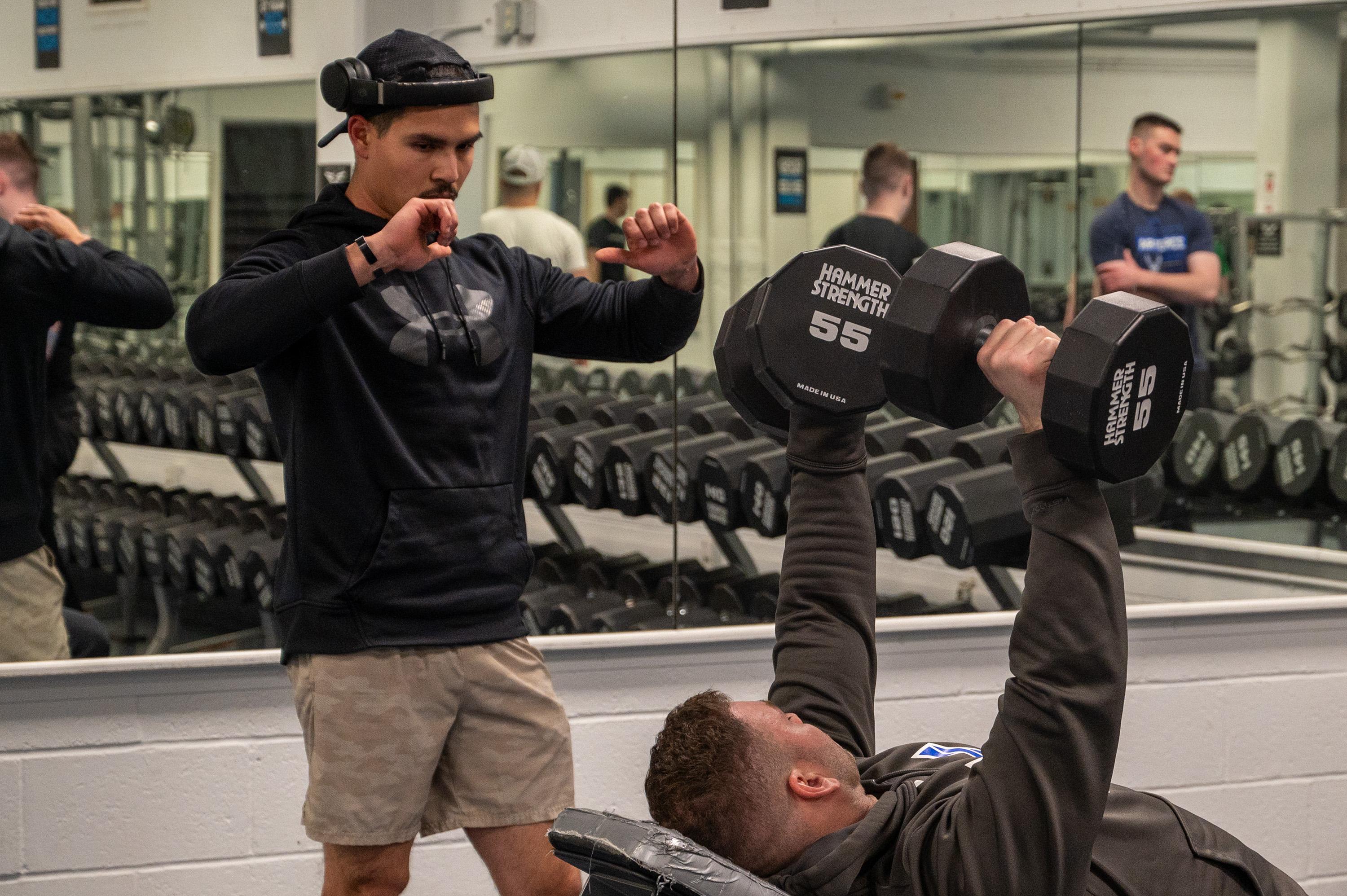 U.S. Air Force Maj. Miles Stutes, 354th Medical Group Operational Support Team physical therapist (right) demonstrates correct form to Senior Airman Ricardo Siqueiros