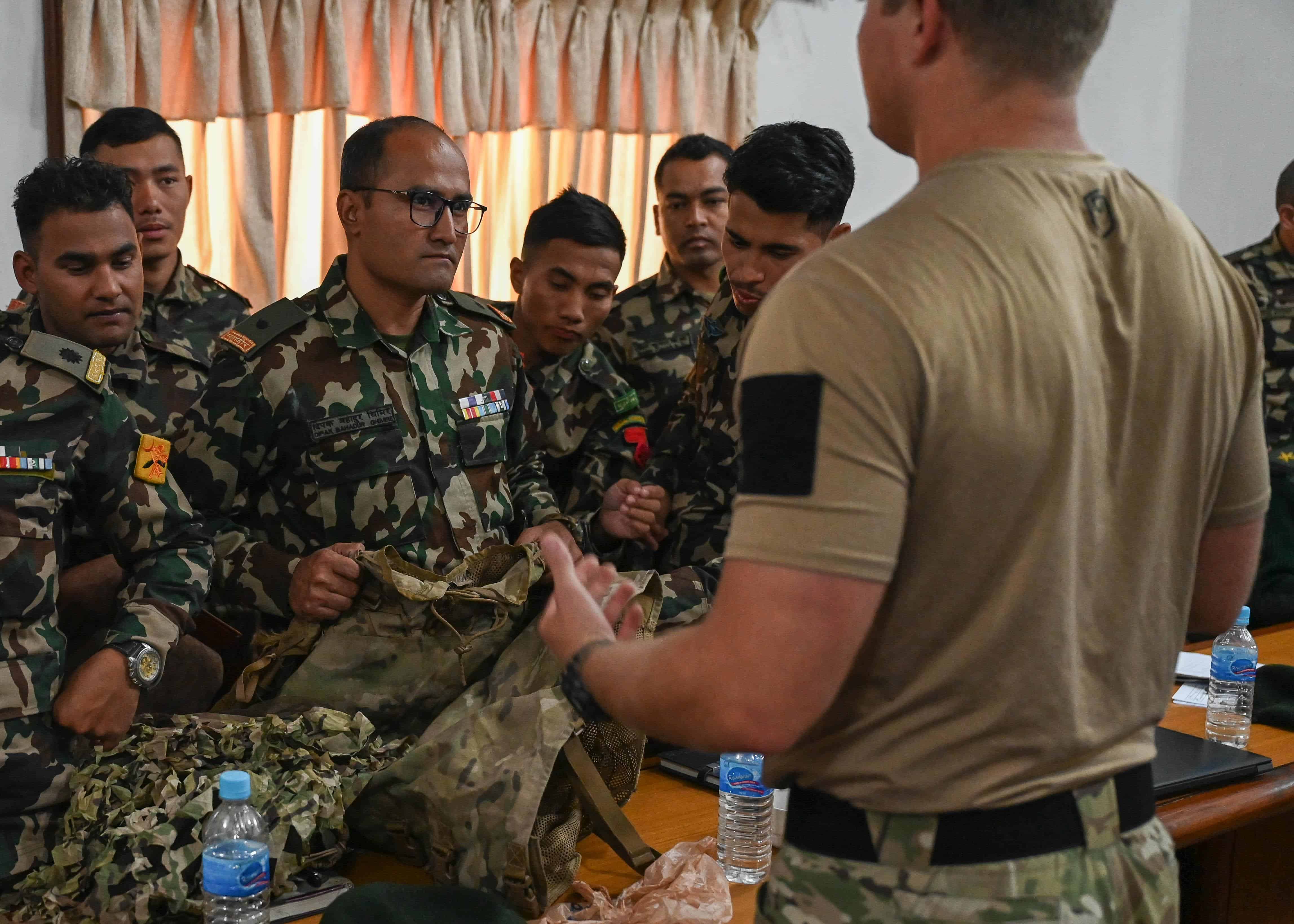 A U.S. Naval special warfare operator discusses camouflage techniques with members of the Nepali Army and Nepali Special Operations Force (SOF) Brigade during a subject matter expert exchange at Ganesh Kashya, the Nepali Army headquarters in Kathmandu, Nepal.