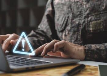 Warning system problem should be careful, Prevent data leaks and maintenance system concept, Soldier in camouflage uniform working on laptop with warning icon.