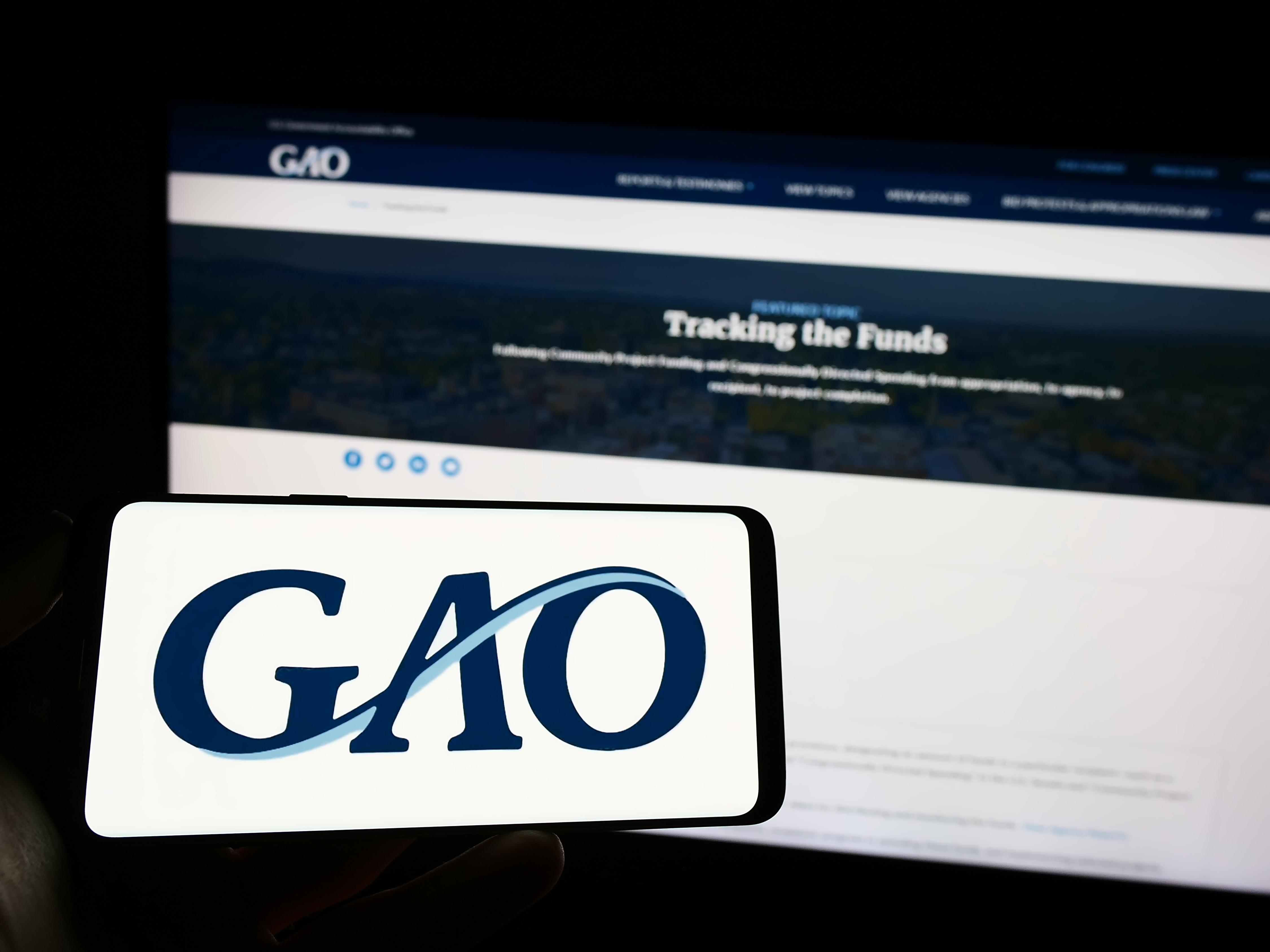 Stuttgart, Germany - 04-23-2023: Person holding mobile phone with logo of US Government Accountability Office (GAO) on screen in front of web page. Focus on phone display. Unmodified photo.