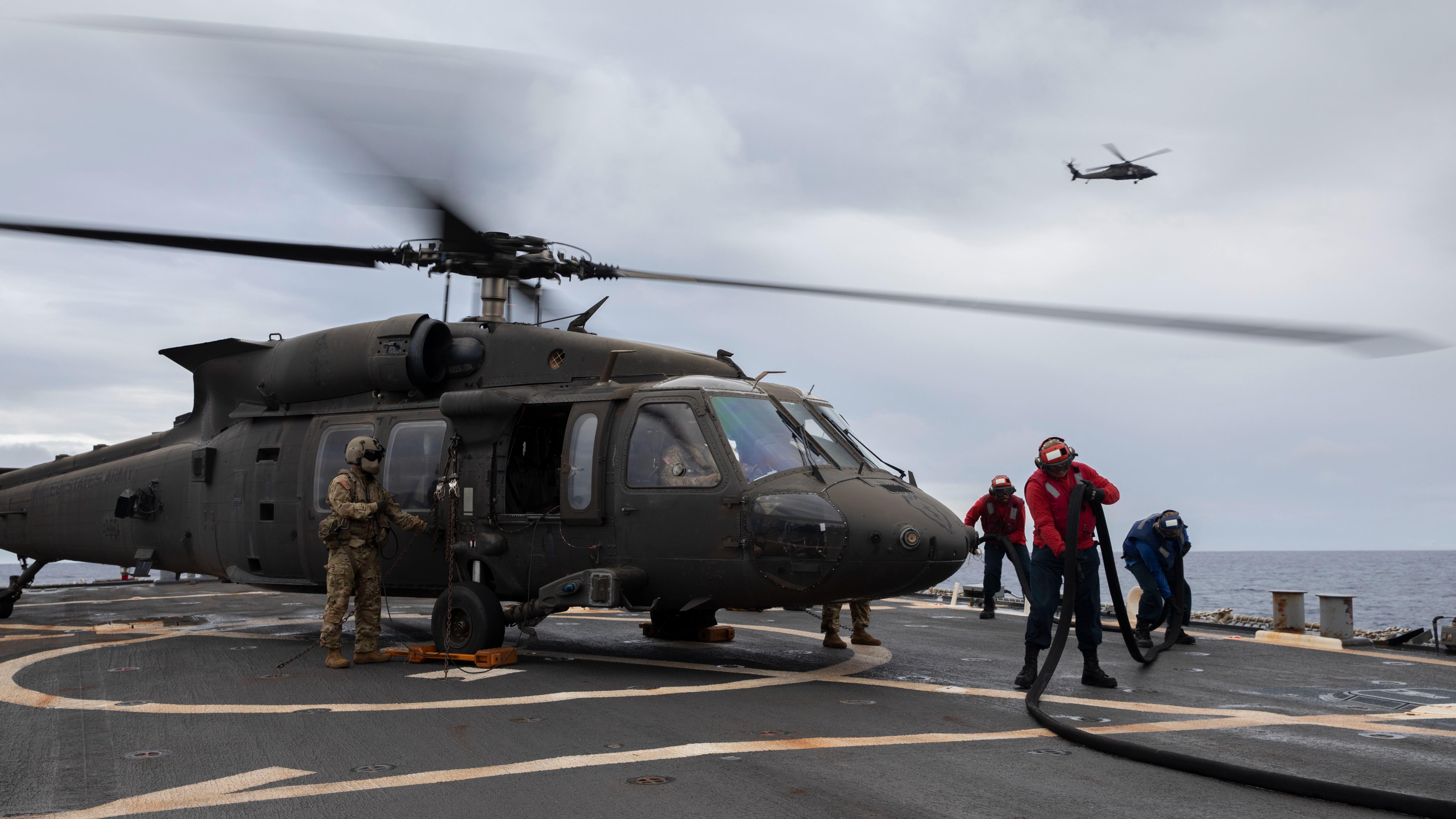 A U.S. Navy crew of boatswain mates work together to refuel a U.S. Army UH-60 Blackhawk helicopter during deck landing qualifications aboard USS John Paul Jones, off the coast of Oahu, Hawaii, November 15, 2021. Deck landing qualifications are conducted annually to maintain proficiency, allowing continued joint operations and training throughout the Indo-Pacific. (U.S. Army photo by Spc. Matthew Mackintosh, 28th Public Affairs Detachment)