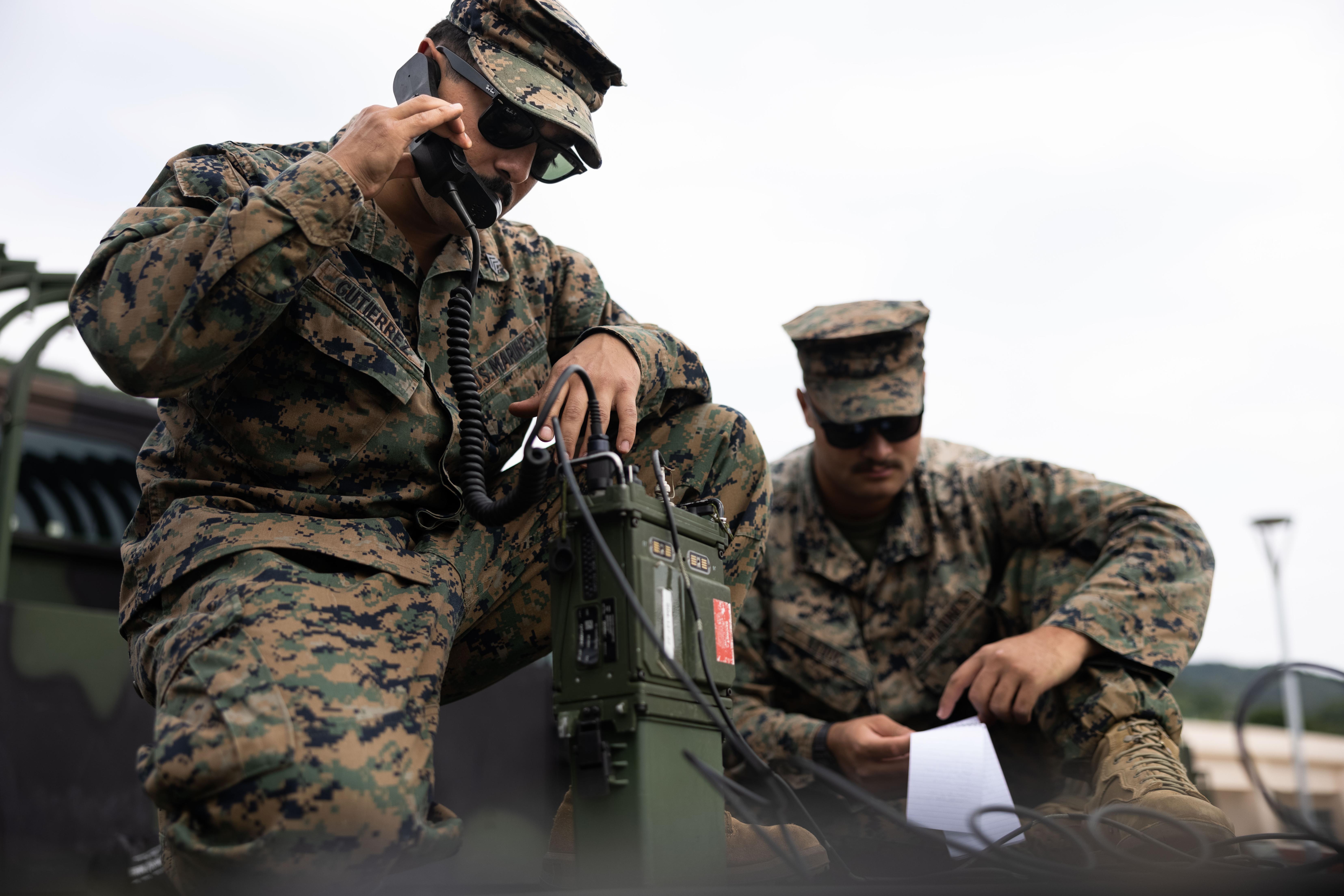 U.S. Marine Corps Sgt. Sebastian Gutierrez, (left), a network administrator, and Cpl. Elijah Leduc, (right), a tactical air defense controller, with Marine Air Control Squadron 4, 1st Marine Aircraft Wing, conduct radio checks on an AN/PRC-117G radio during the field training exercise portion of Resolute Dragon 23 at Japan Ground Self-Defense Force Camp Ishigaki, Okinawa, Japan, Oct. 15, 2023.