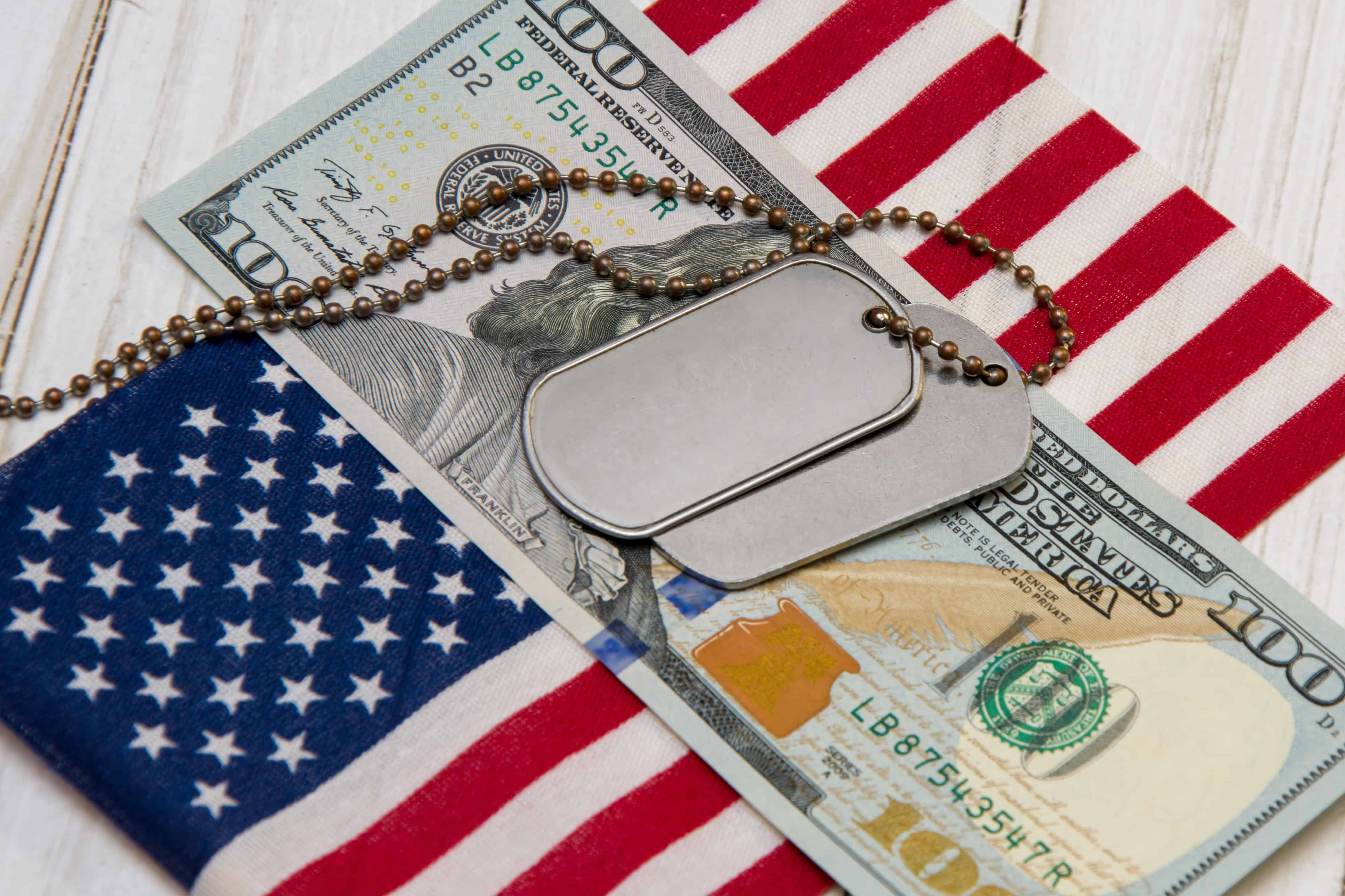 An army medallion lies on a dining bill against the backdrop of the American flag. Financial assistance to the military, army salary, cost of living and military operation. State support for military