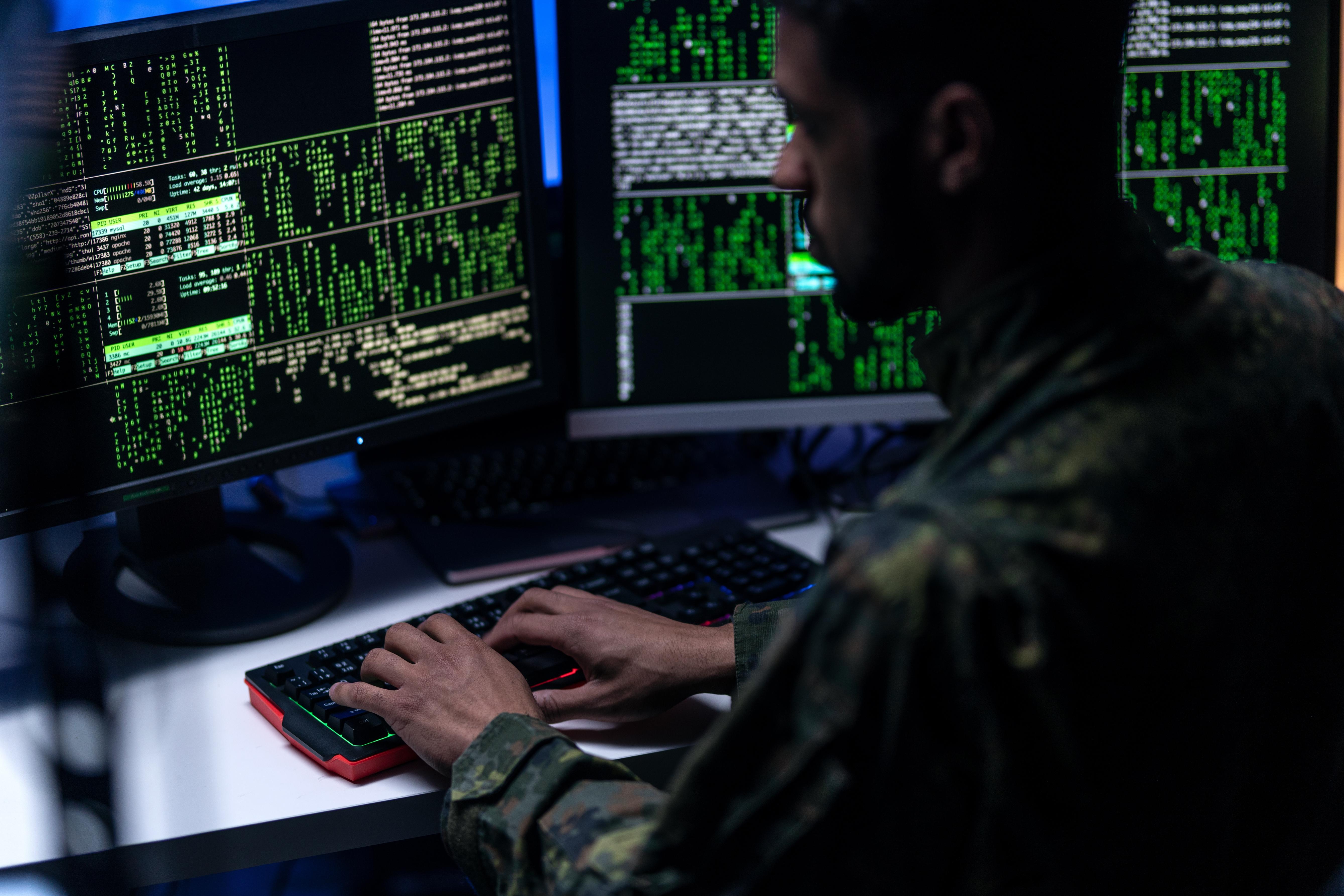 Hacker in military unifrorm on dark web, cyberwar concept.